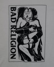 Load image into Gallery viewer, A white t-shirt featuring the &quot;Nuns Kissing&quot; graphic from the punk rock band Bad Religion. The bold design captures the rebellious spirit of the band, showcasing iconic imagery. Made from 100% cotton for a soft, breathable feel, this shirt is available in unisex sizes from Small to 2XL, perfect for punk rock enthusiasts and those who appreciate edgy, statement-making fashion.
