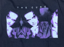 Load image into Gallery viewer, A high-quality, classic-fit unisex band t-shirt featuring a bold graphic inspired by The Cure. Made from 100% cotton, this soft and breathable tee is available in sizes Small to 2XL, offering all-day comfort and style. Ideal for fans of the legendary band, it’s the perfect way to showcase your musical passion.
